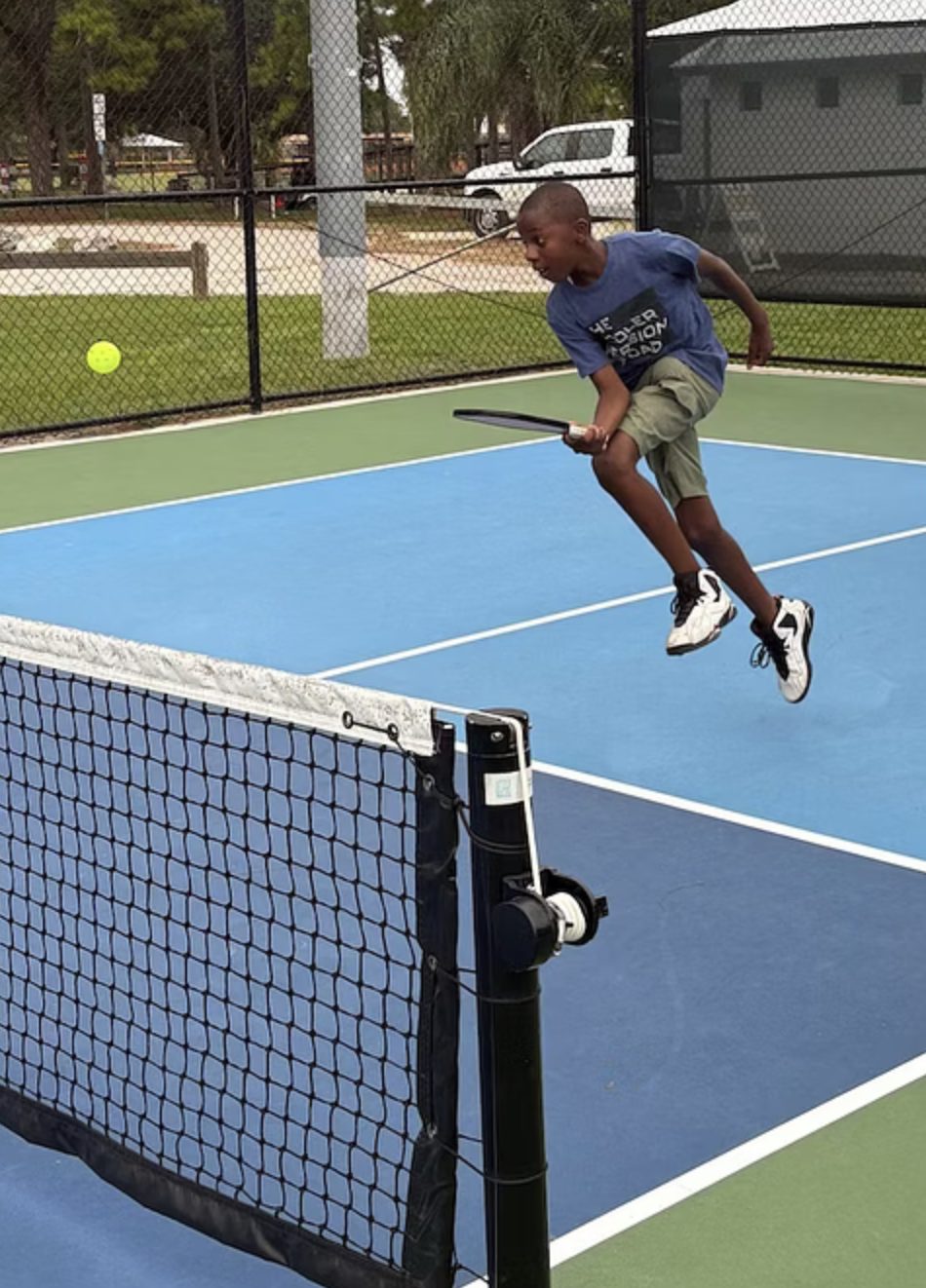 A camper leaping to reach an overhead at the net.