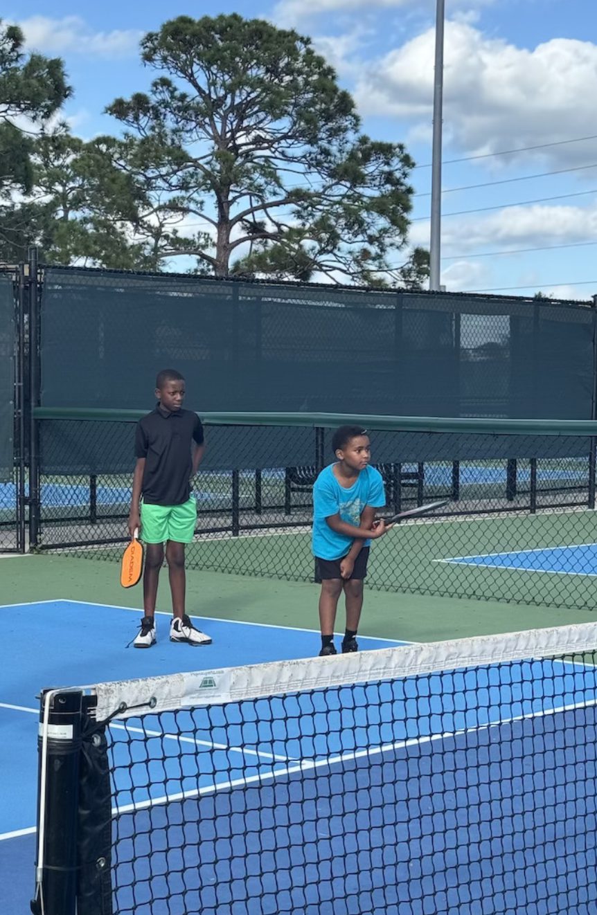 Two boys with paddles waiting to receive on a blue court.