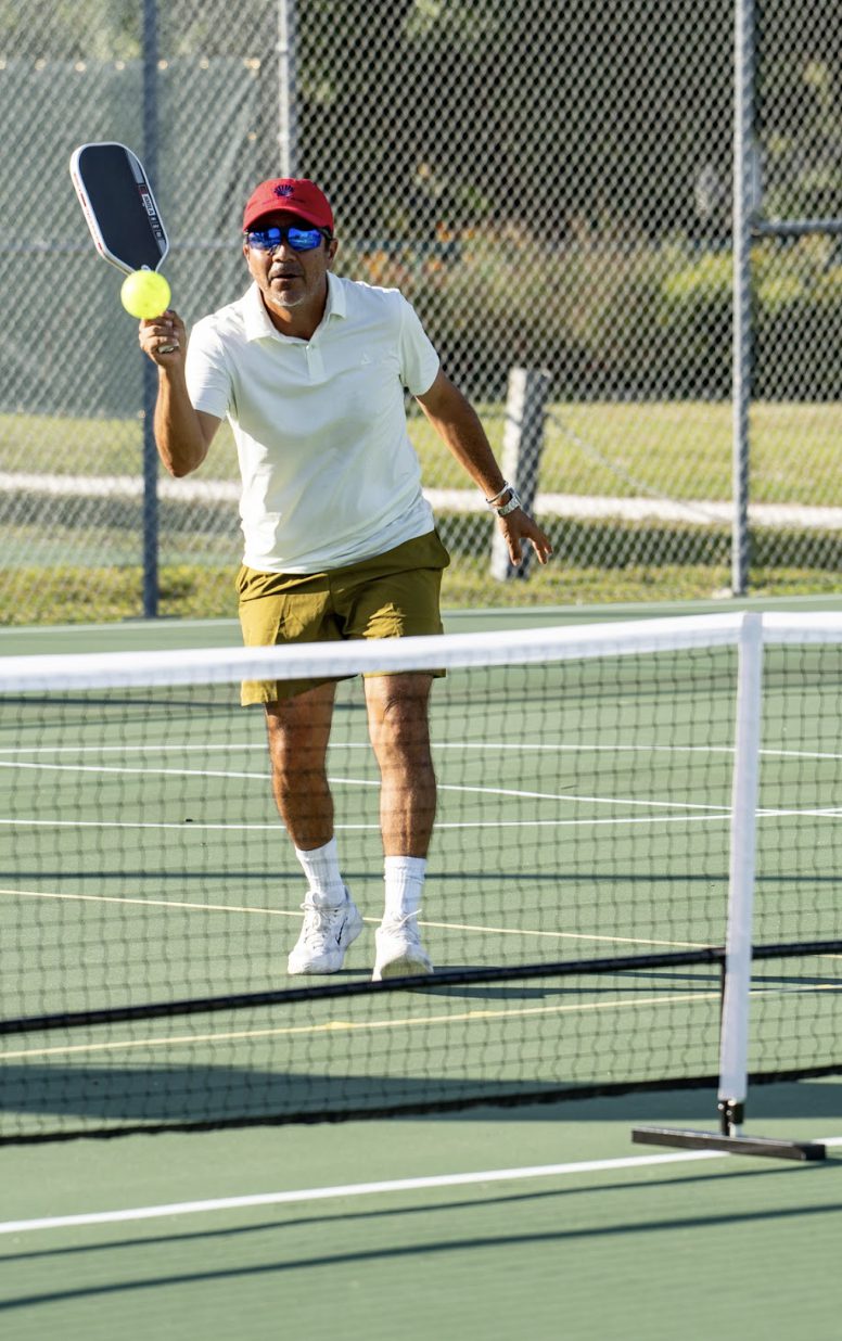 A local pro hitting a forehand volley at the net.