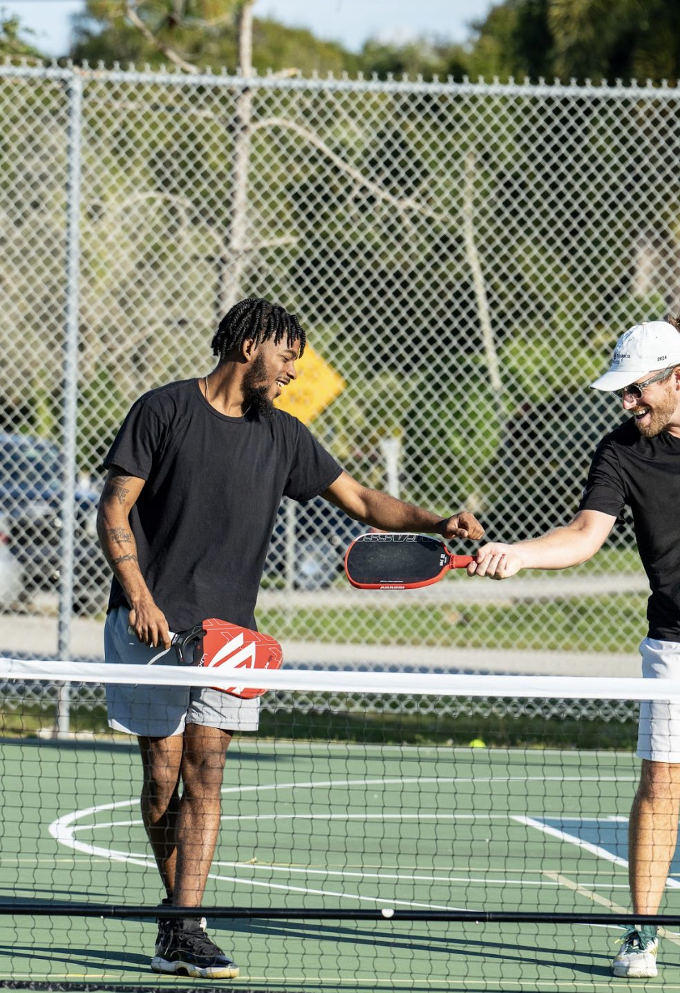 Two players tapping paddles across the net after a point.