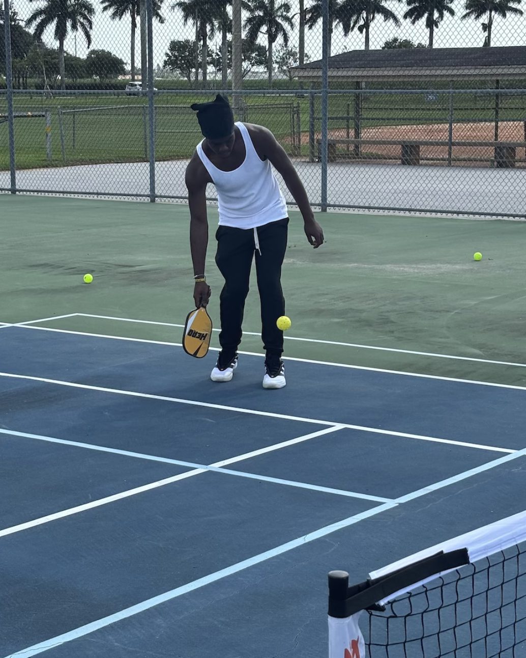 A player scooping up a ball with a paddle between points.