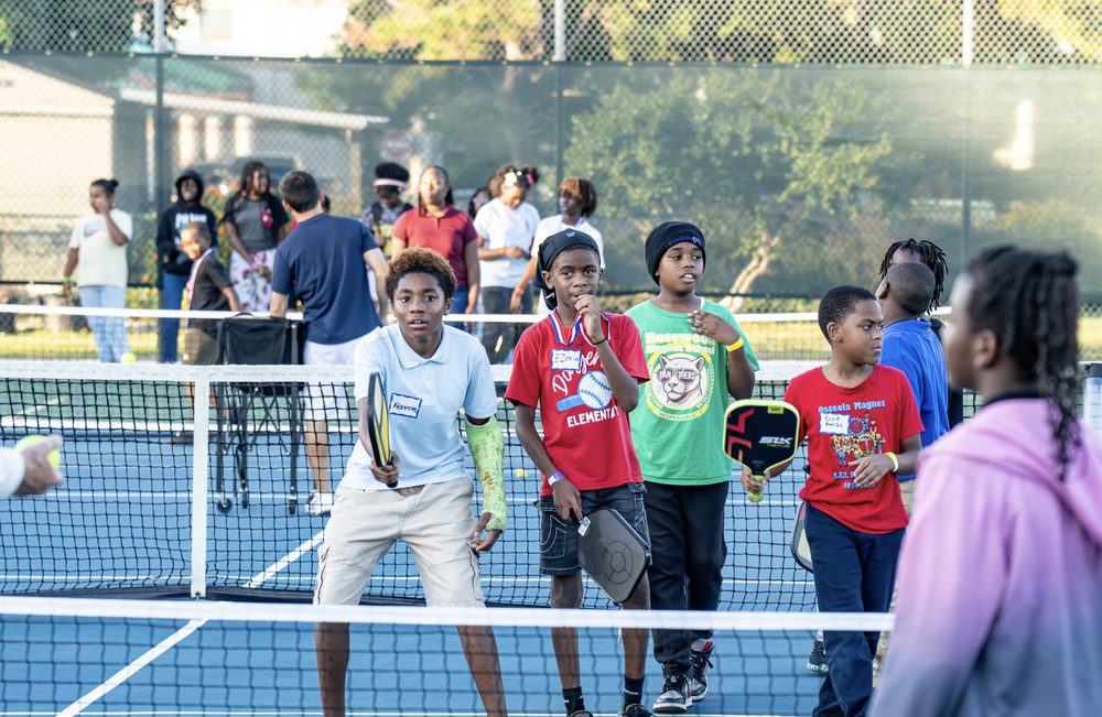 A group of kids in name tags lined up along the net.