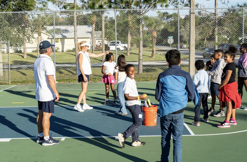 Campers and volunteers moving between stations on the courts.