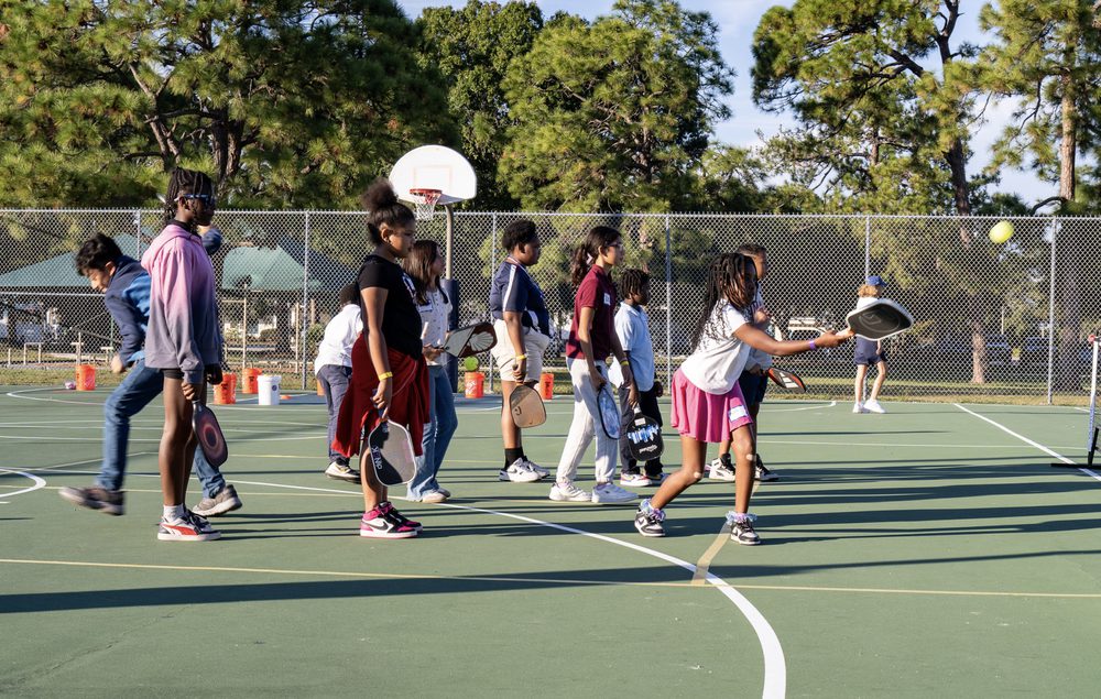 Kids playing on a court beneath a basketball hoop.