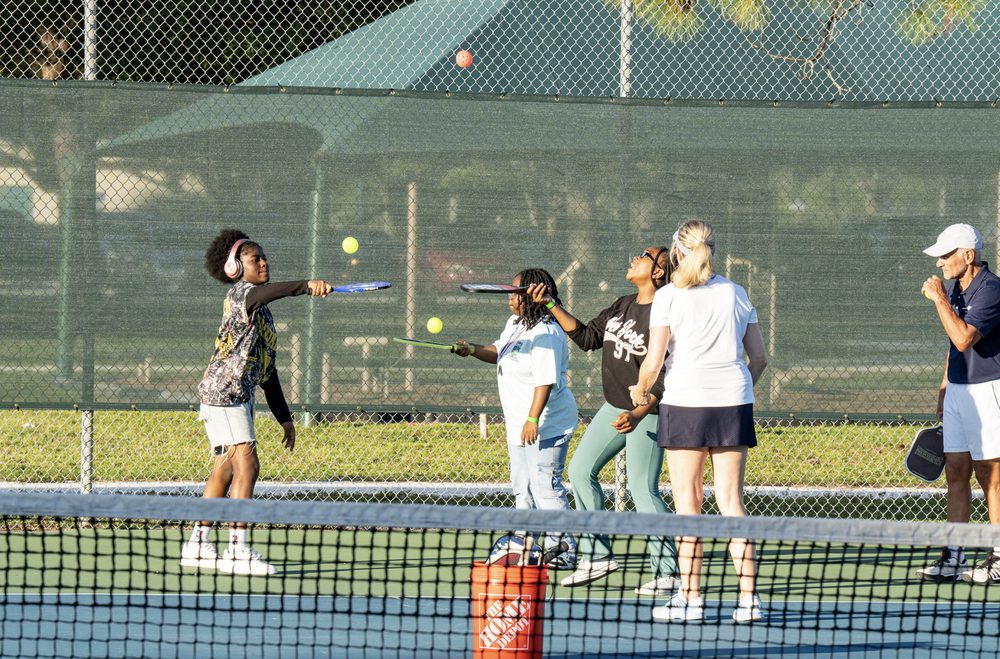 A boy hitting a ball while a group waits their turn behind him.