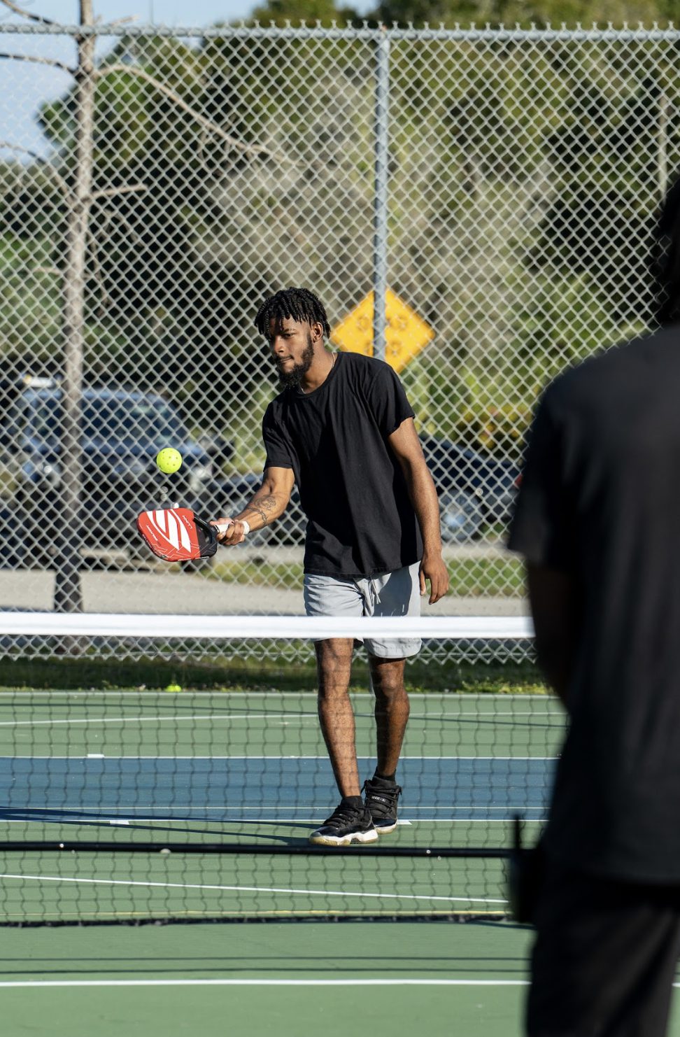 A young player dropping a ball to start a serve.