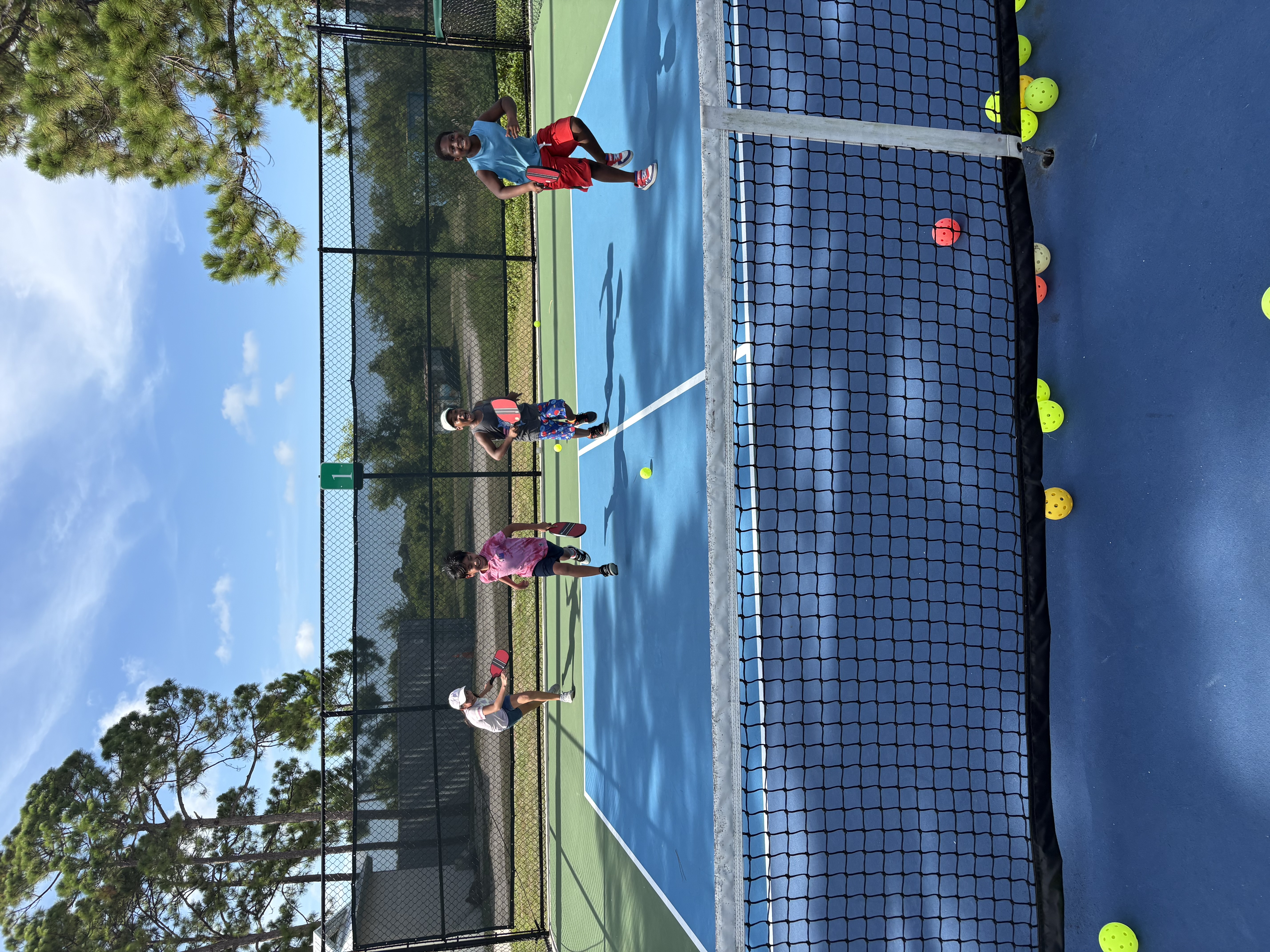 Four campers running up the court toward the net during a movement drill.